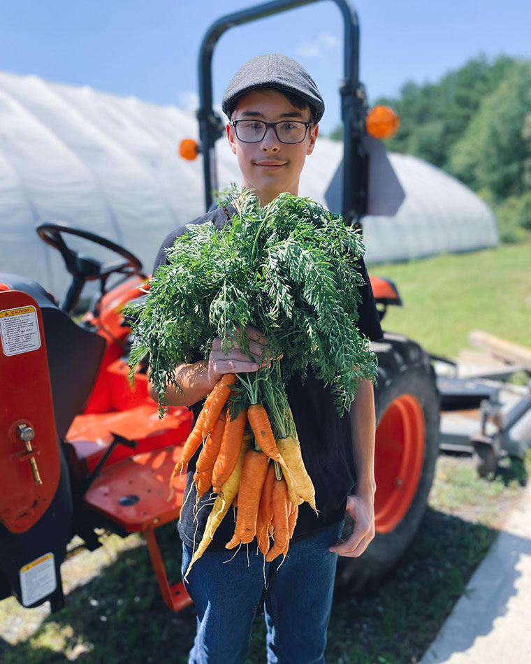A student holds a bunch of carrots grown in the MeANS  1-Acre Farm